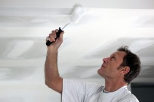 Man painting ceiling white 